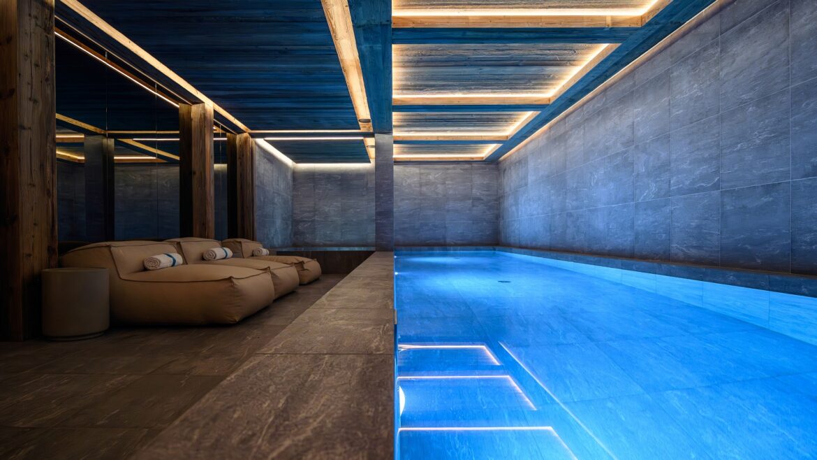 indoor spa pool at ski chalet with bright blue water contrasting with raw concrete walls