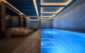 indoor spa pool at ski chalet with bright blue water contrasting with raw concrete walls