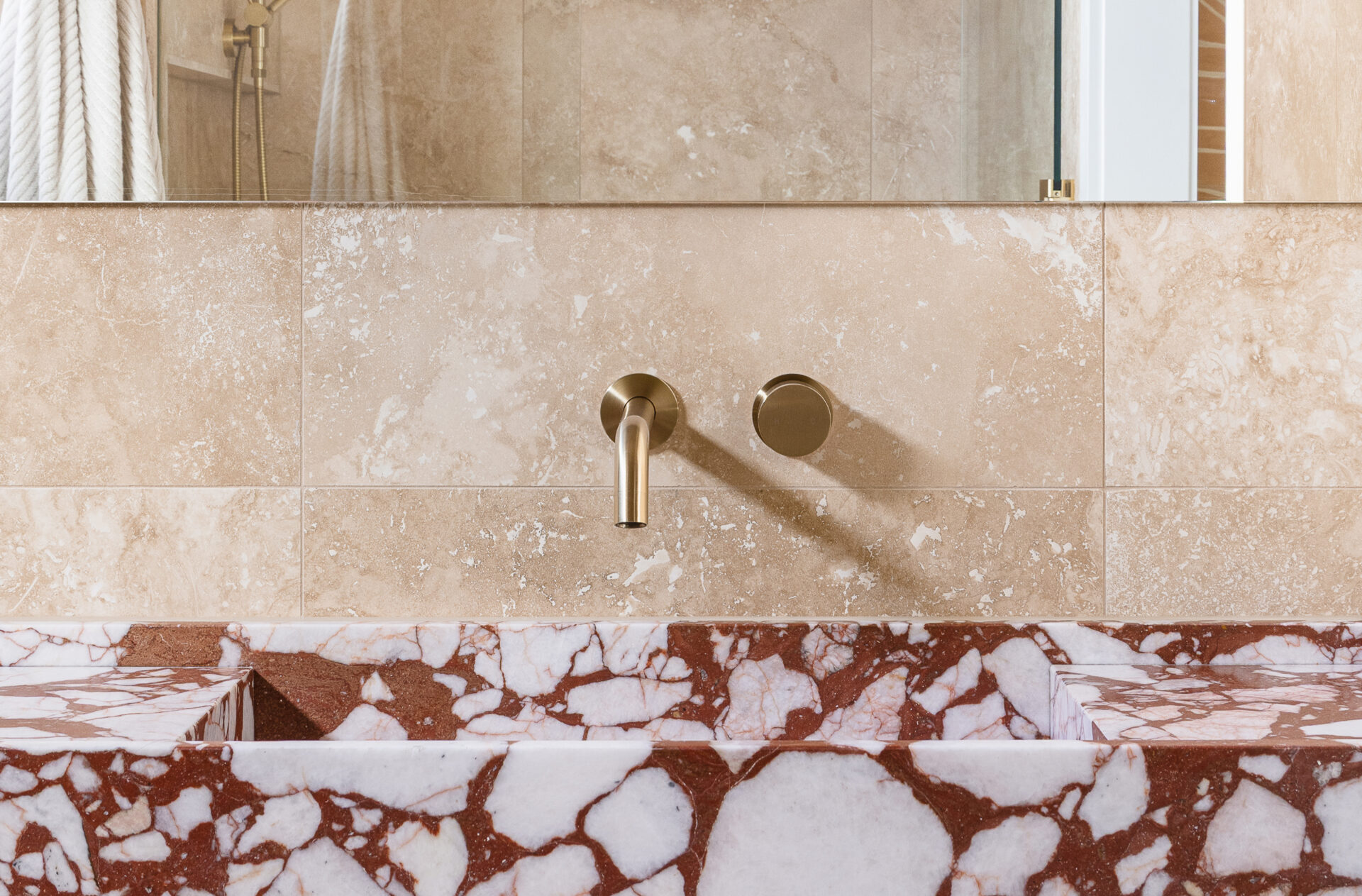 ABI Interiors brass tap above red and white marble sink