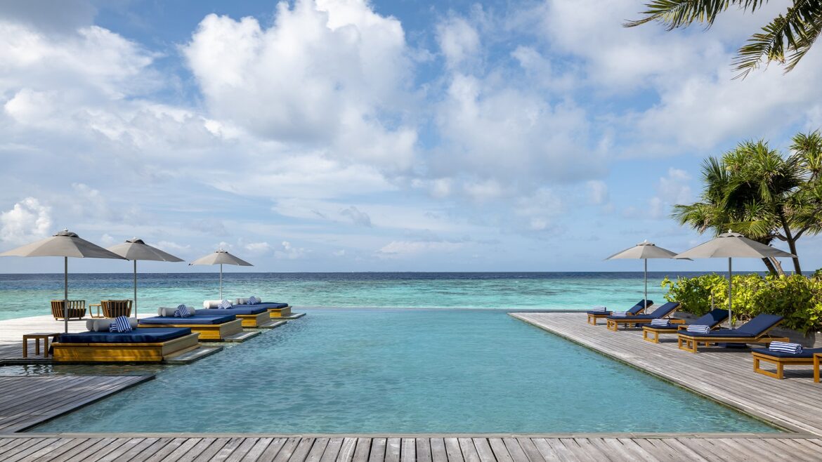 hotel infinity pool surrounded by wooden deck extending out to sea on island in the Maldives