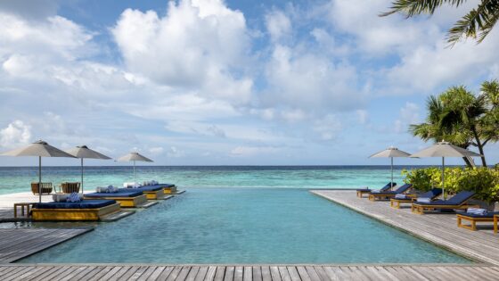 hotel infinity pool surrounded by wooden deck extending out to sea on island in the Maldives