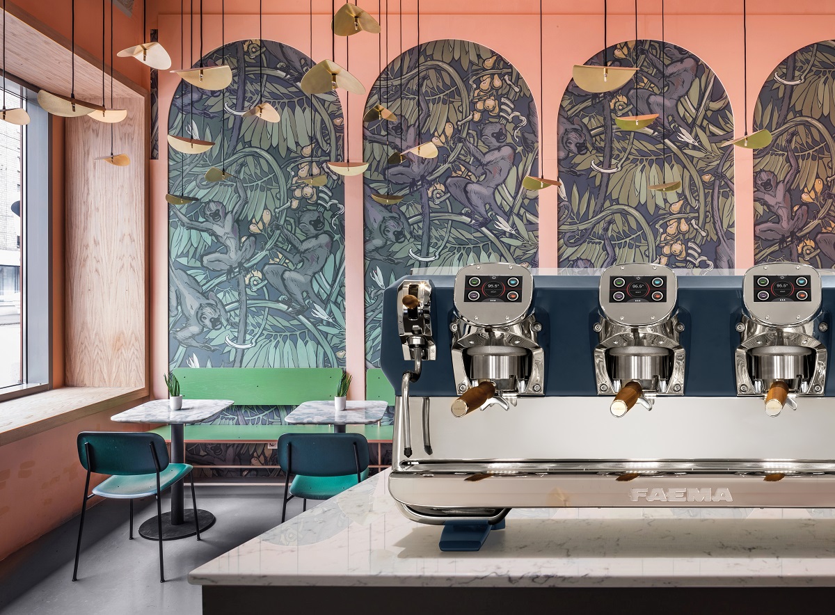 Cimbali Faema coffee machine on counter in front of pink walls with tropical wallpapered alcoves