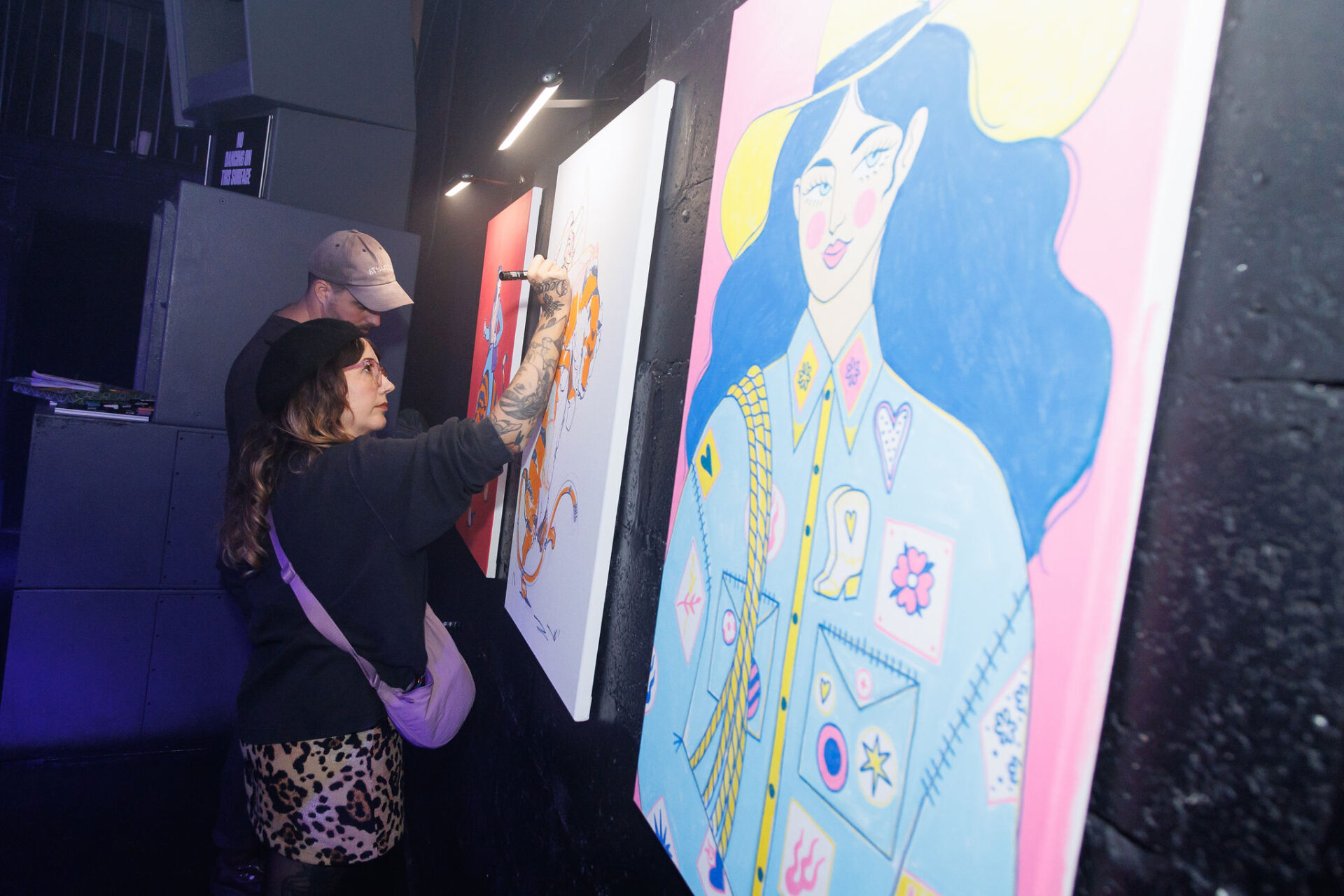 two artists, Zach Kremer and Jessica Sharville, painting canvases at The Brit List Awards 2025