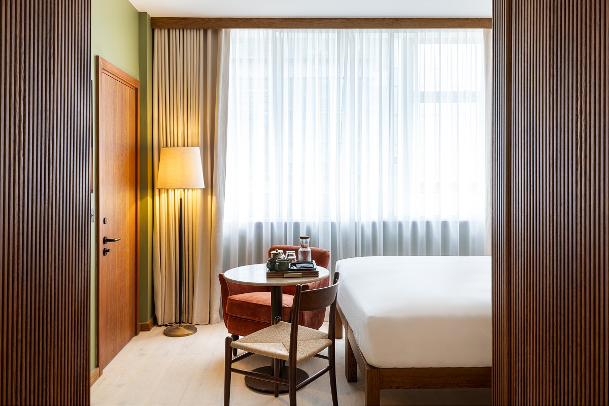 table and chair at footend of bed in hotel guestroom