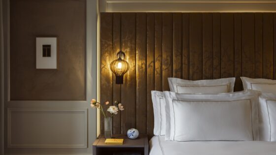 detail of bed with white linen against panelled headboard and suspended bedside light in Rosewood Amsterdam guestroom