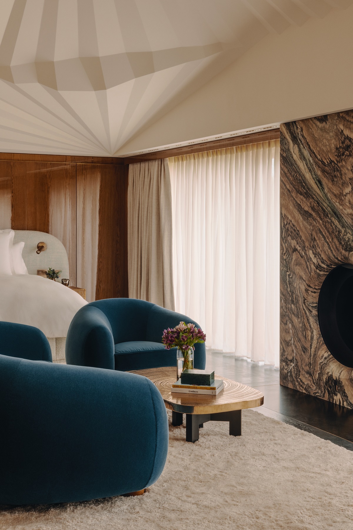 blue chairs in front of fireplace and next to bed