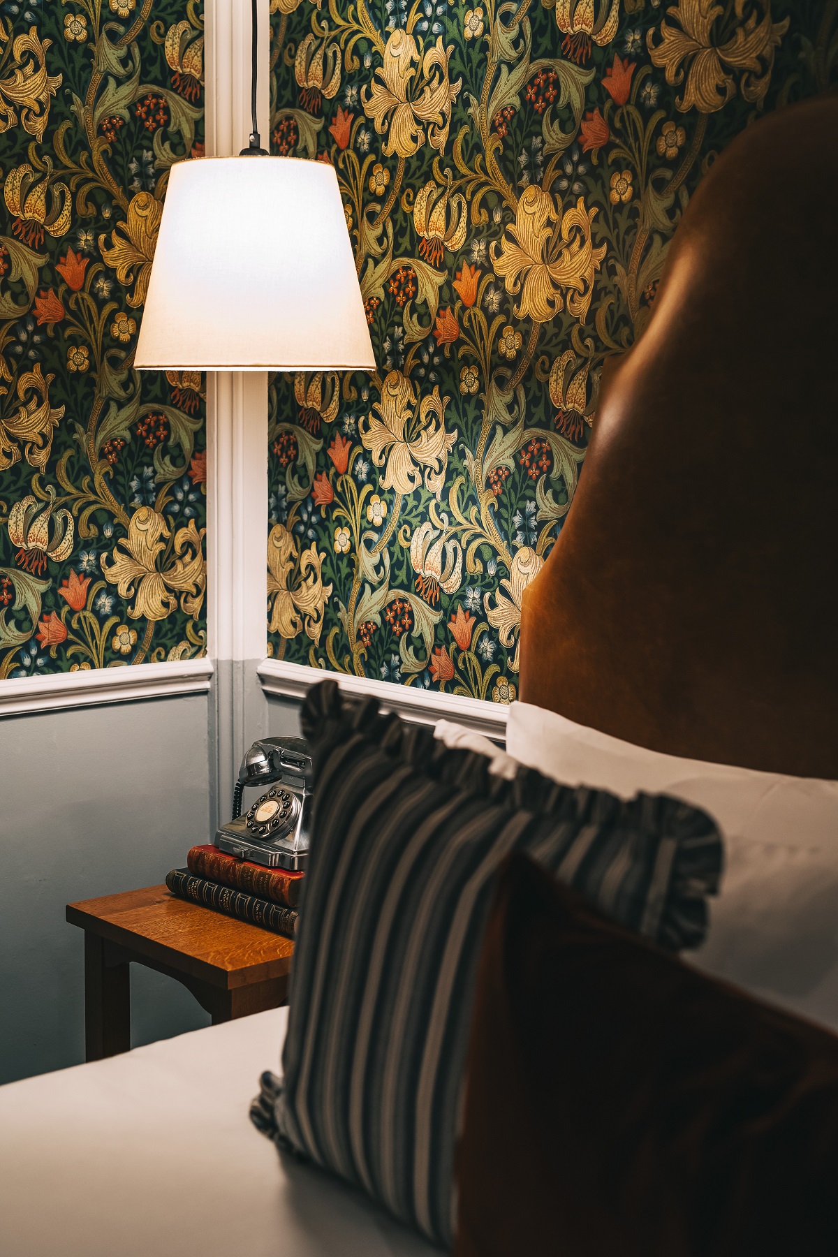 bed detail against floral wallpaper and bedside lamp in Drayton Court