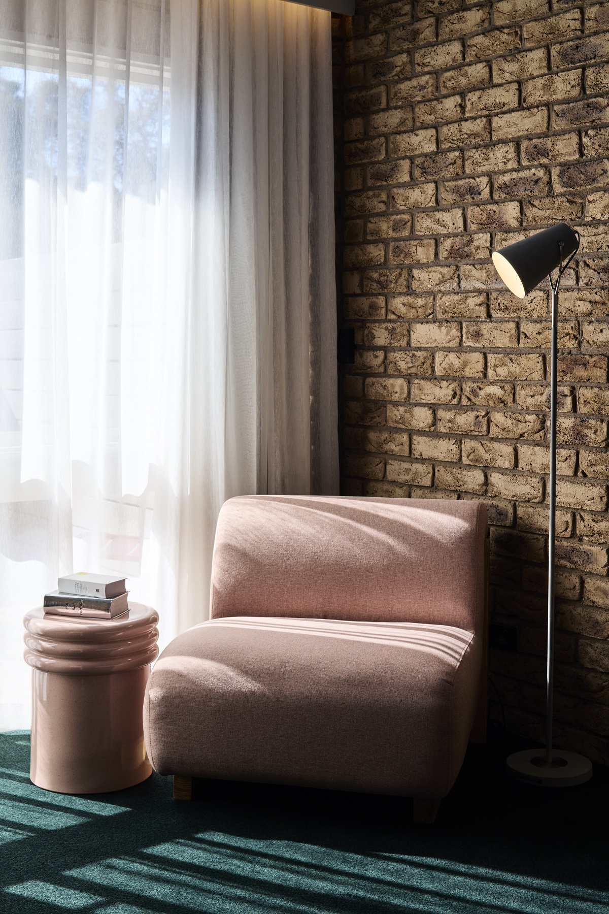 pink chair on green carpet against brick wall