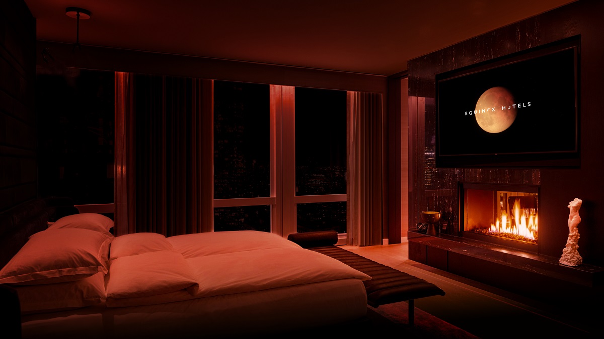 hotel guestroom with white mirror equinox logo on screen above fireplace