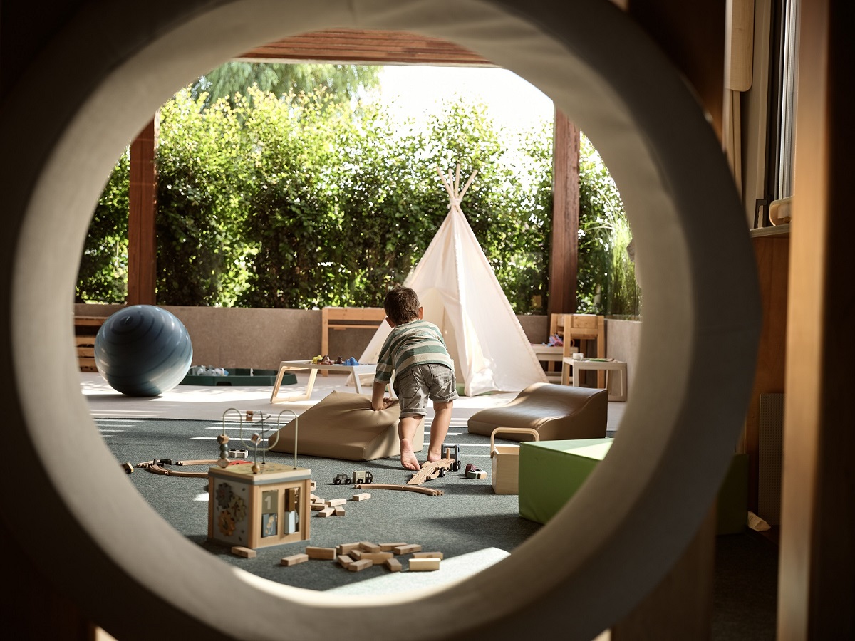 view through a porthole window to outdoor play area in Fiori Kids Club at Contessina Hotel, designed by Worldwide Kids