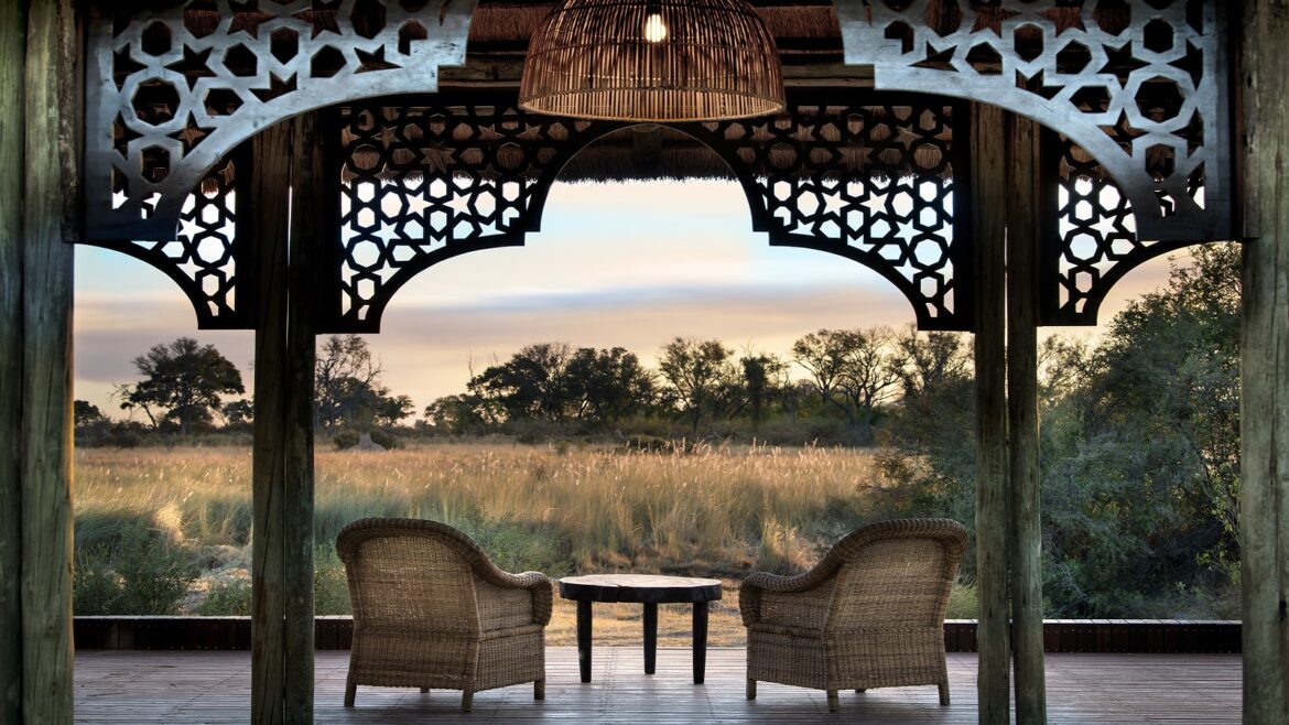 two wicker chairs framed by building looking out over african savannah view