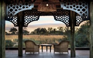 two wicker chairs framed by building looking out over african savannah view