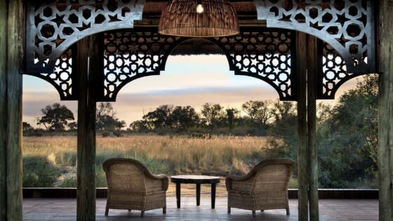 two wicker chairs framed by building looking out over african savannah view