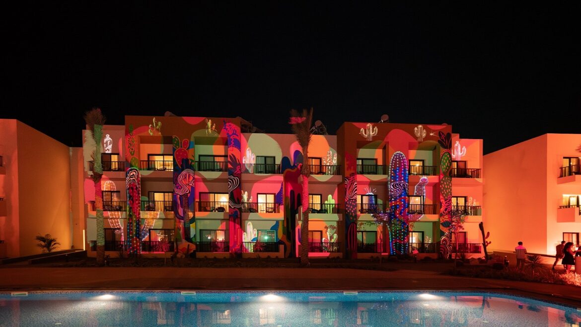 night lights across pool and cactus mural at Kaktus Hotel & Co-Working Hub, SomaBay