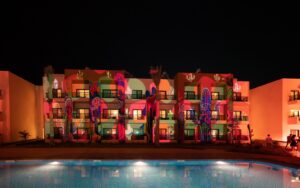 night lights across pool and cactus mural at Kaktus Hotel & Co-Working Hub, SomaBay