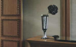 vase on wooden surface with single black flower