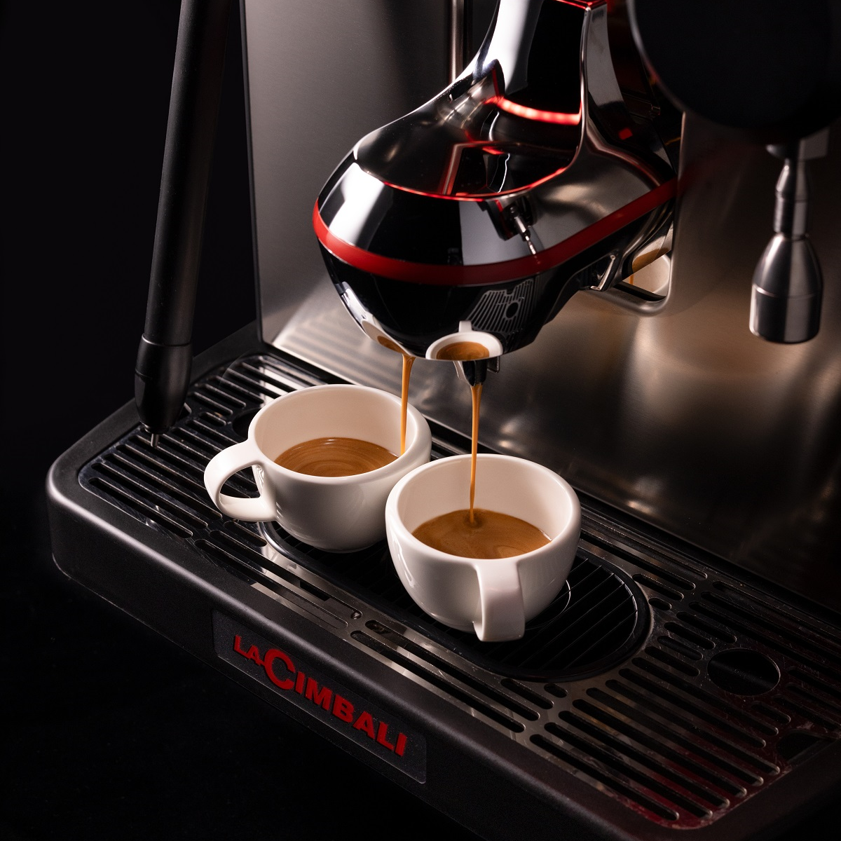 two espresso cups on coffee machine with coffee pouring in
