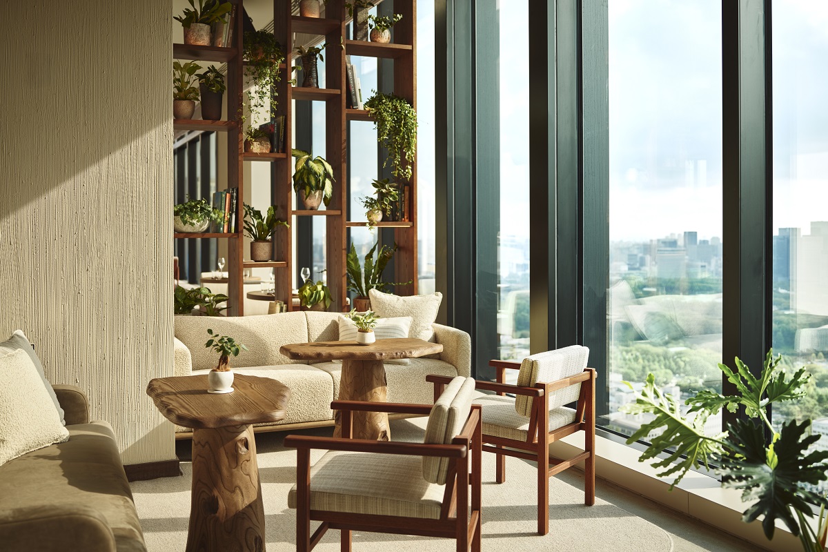 wooden and cream furniture with sjelves and plants in front of windows with panoramic view over Tokyo