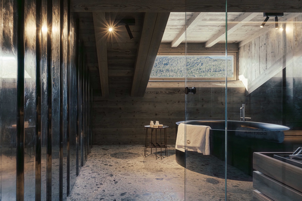 black freestanding bath on stone floor under wooden eaves in Rosapetra suite with mountain view