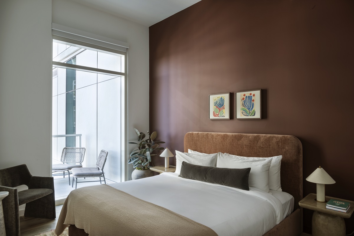 bedroom with white linen on bed set against brown feature wall