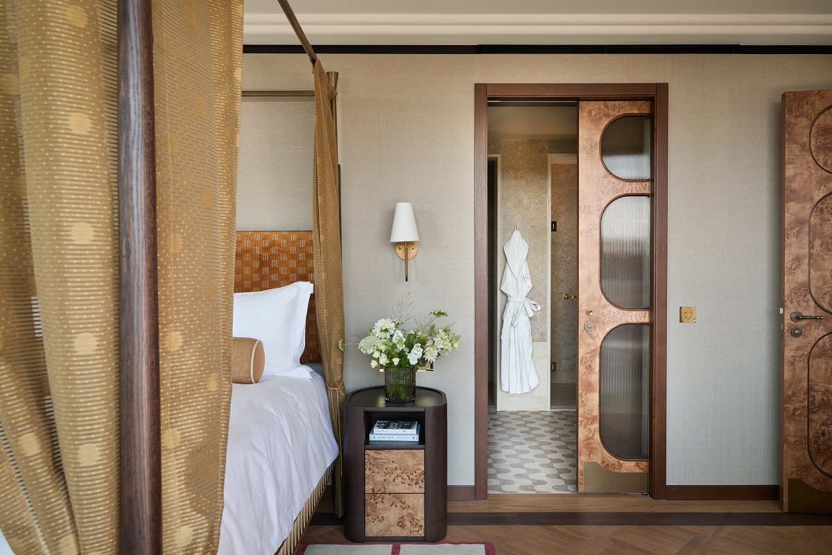 view from edge of bed with draped curtain looking though to ensuite bathroom in guestroom at The Newman by Kinsfolk &Co