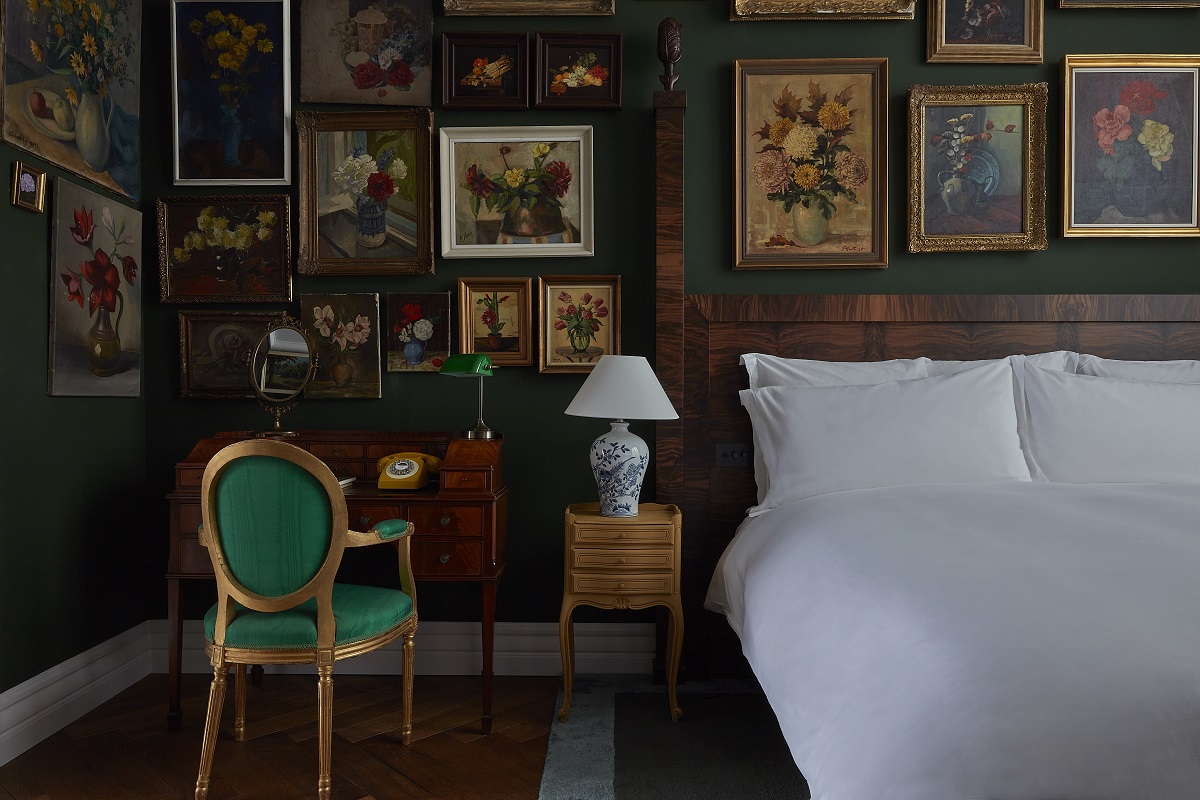 bed in guestroom with wall full of old paintings behind