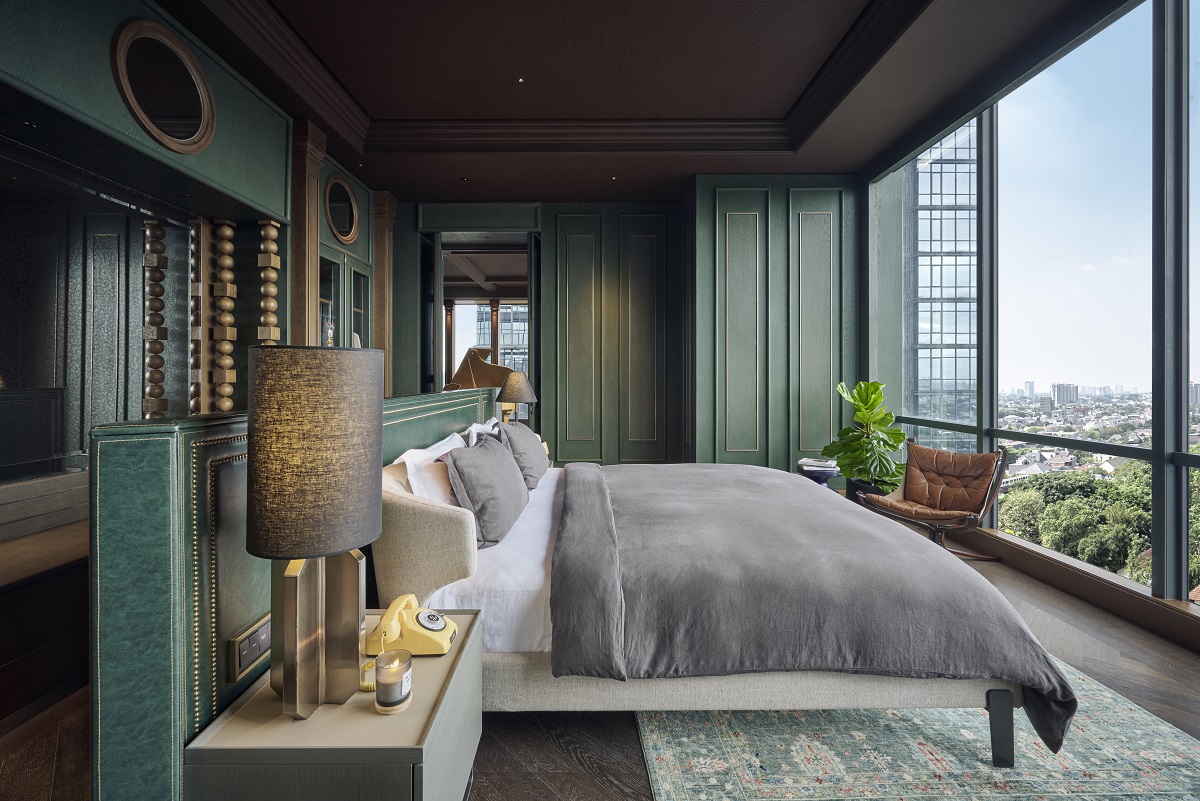 guestroom in Oddbird penthouse suite with bed facing floor to ceiling windows with views over Jakarta