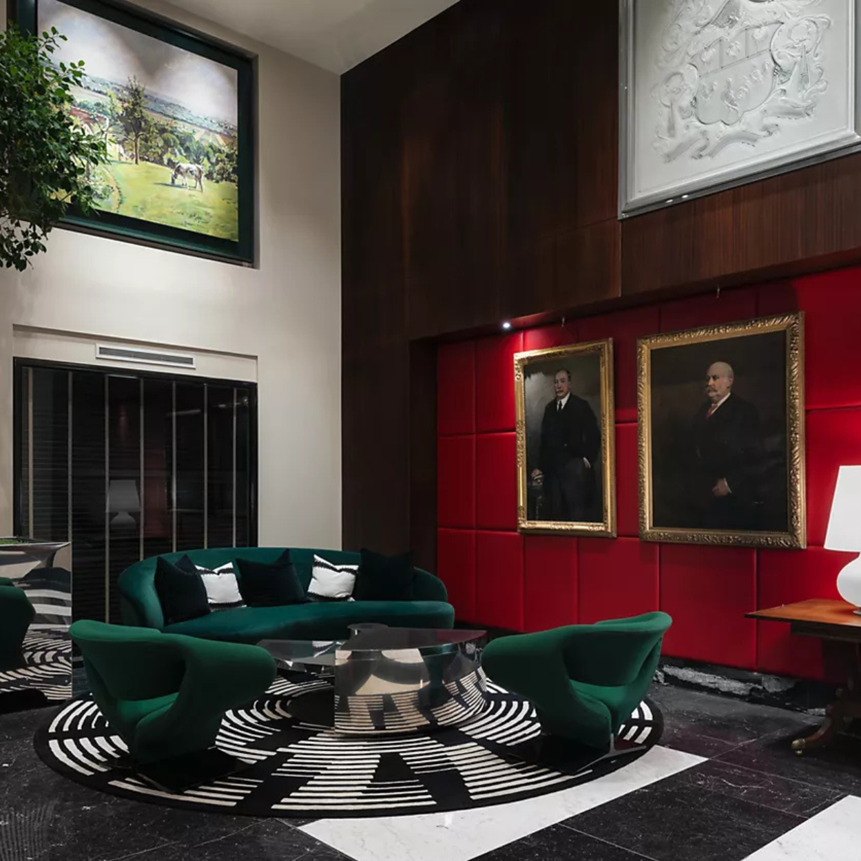 Red quilt-panelled wall of Sofitel London St James lobby space. Wall hosts oil paintings of old bank managers
