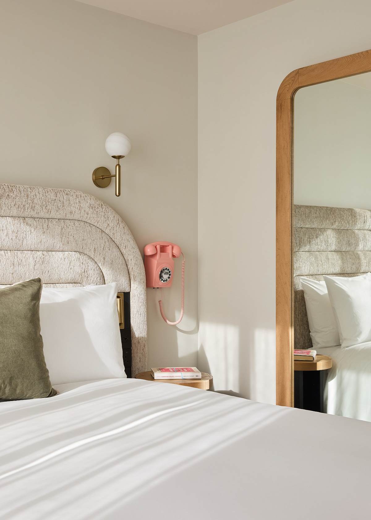 corner detail of hotel indigo bed with pink vintage phone on the wall