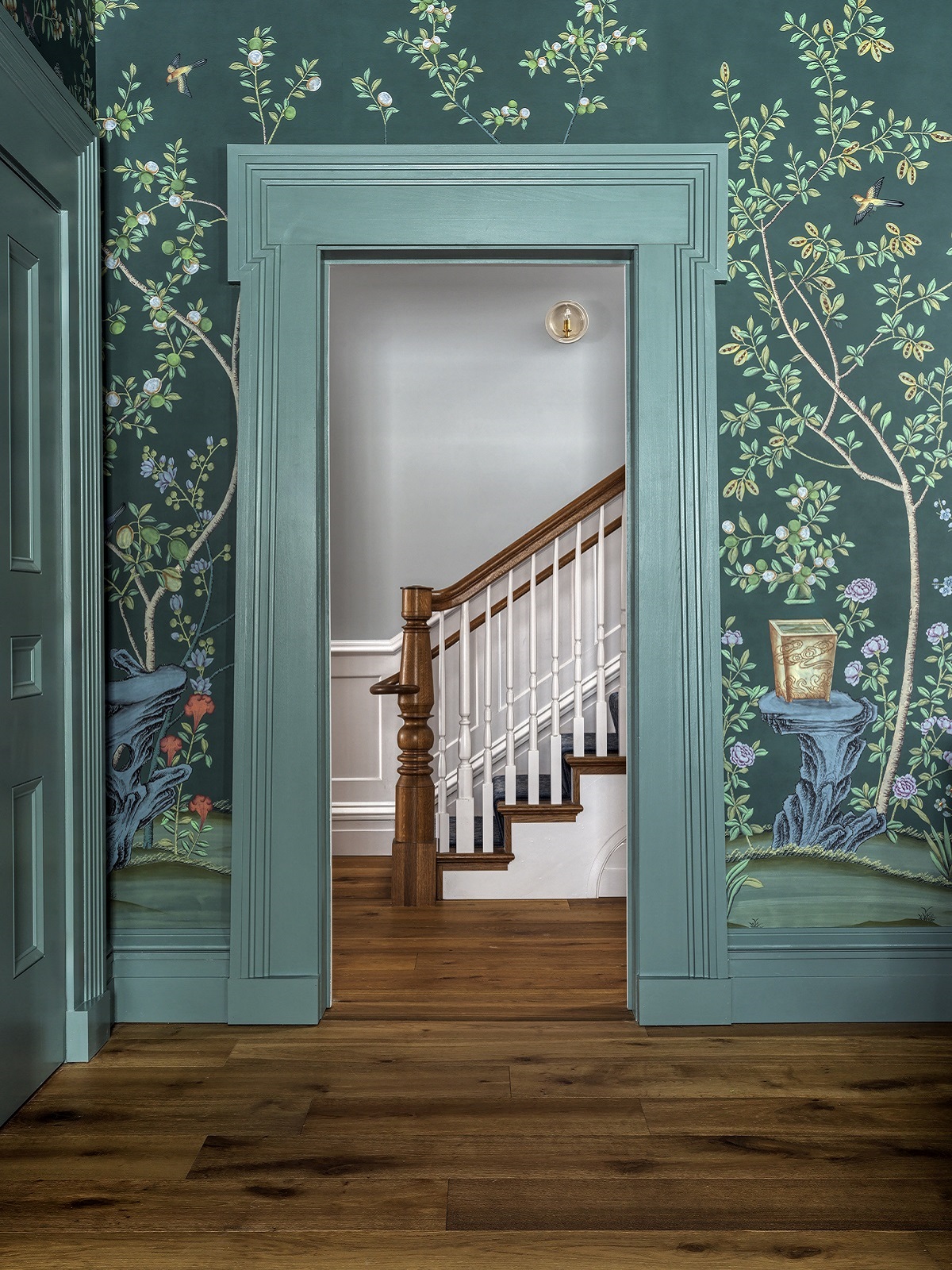 open doorway framed with blue floral wallpaper with view to wooden staircase