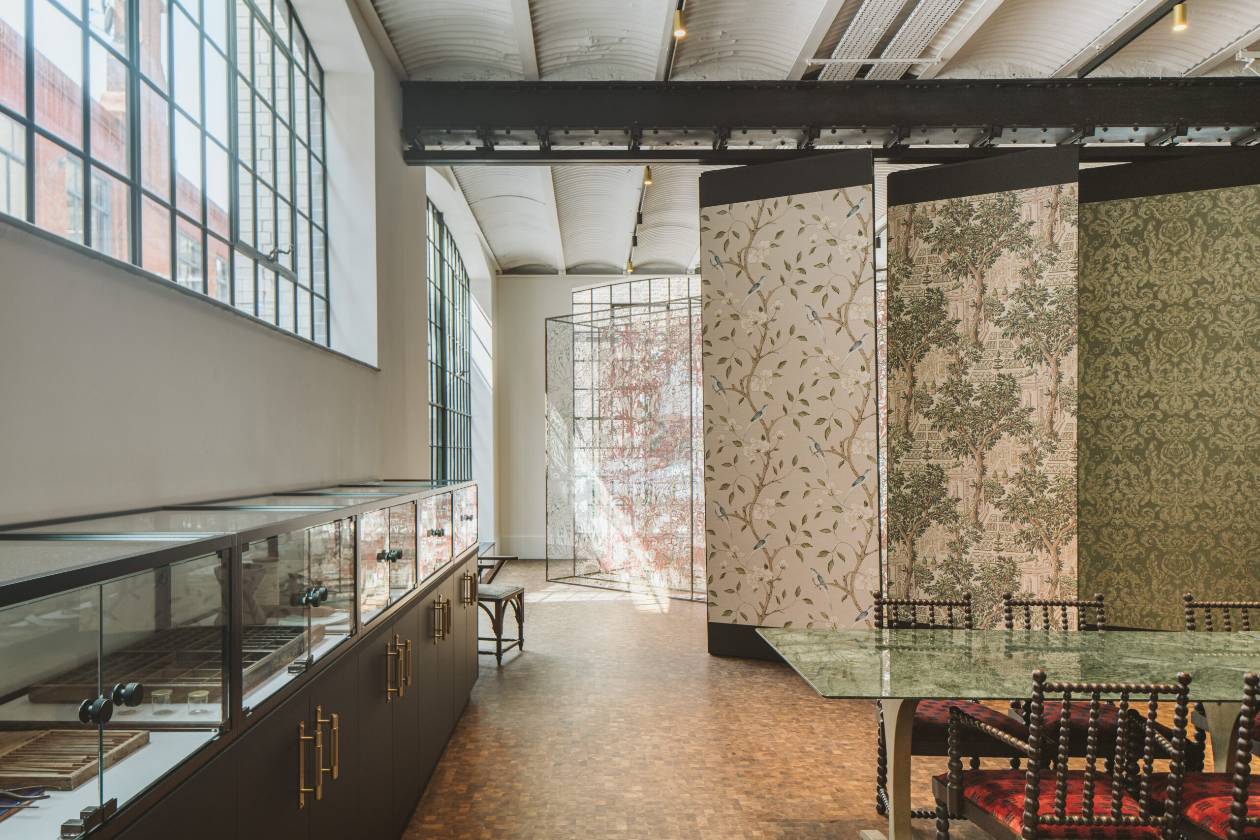 Interior of Sanderson Design Group London HQ, showing glass cases on left and sliding wallpaper segments 