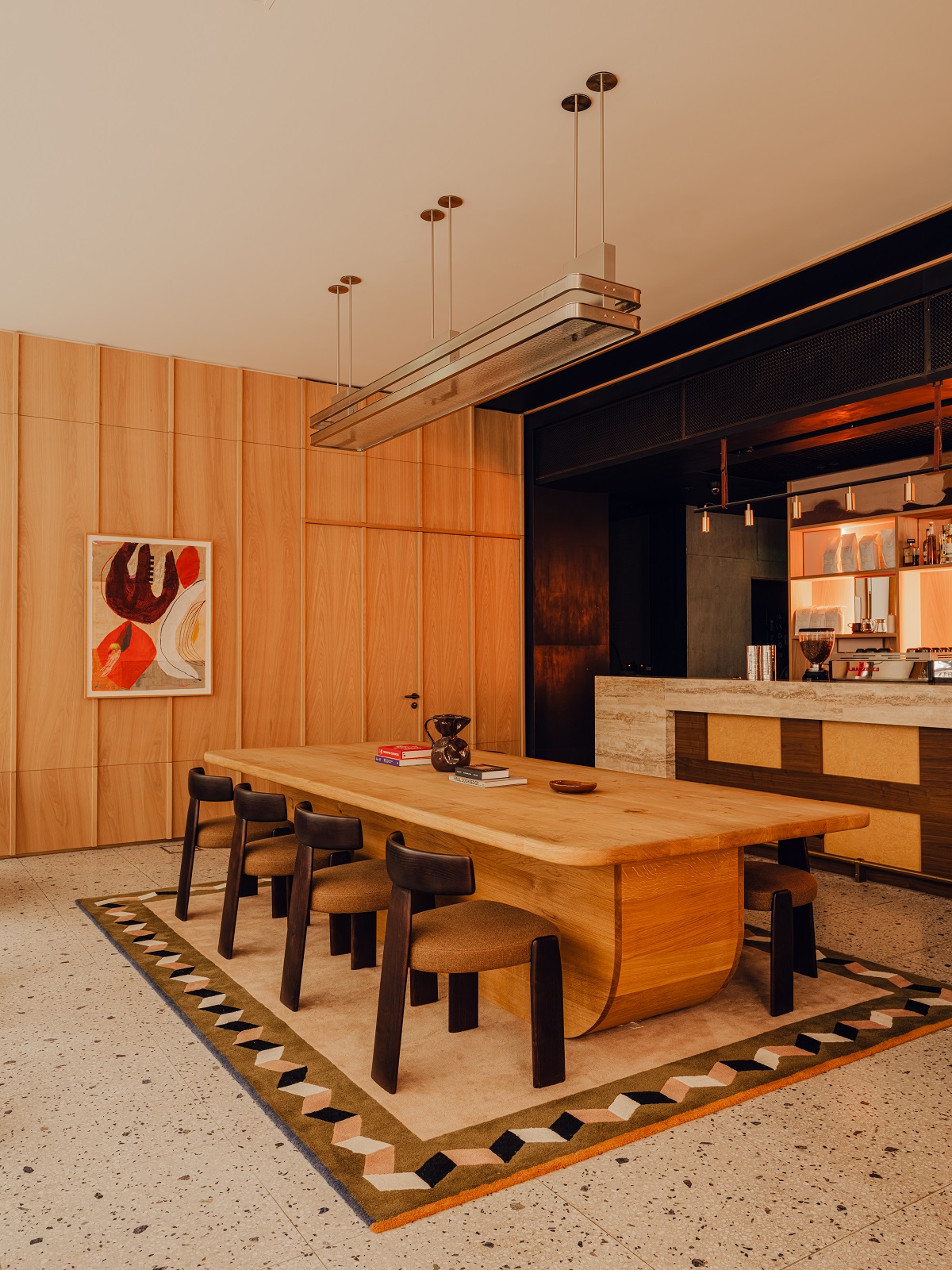 central wooden table alongside bar in cafe area in Aethos London