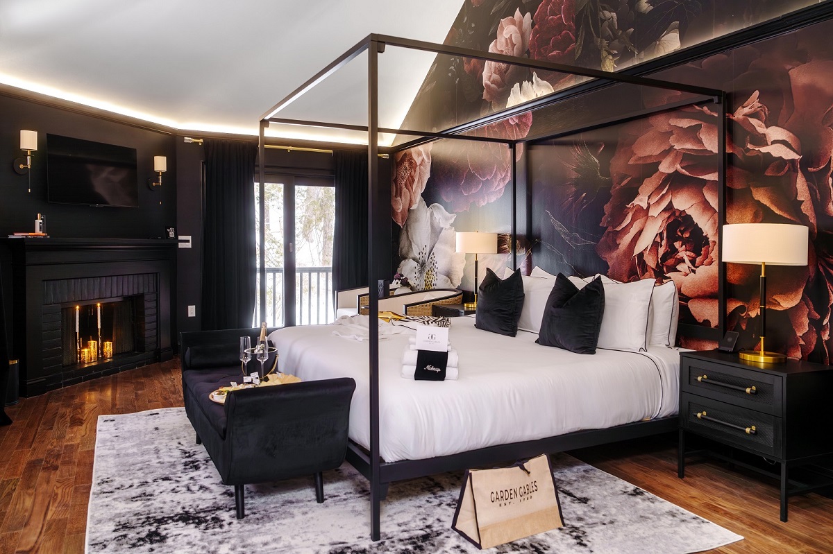 four poster bed in front of oversized dark floral wall covering