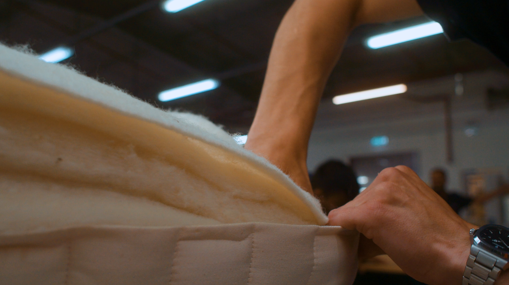 Person stuffing mattress layers at Hypnos factory 