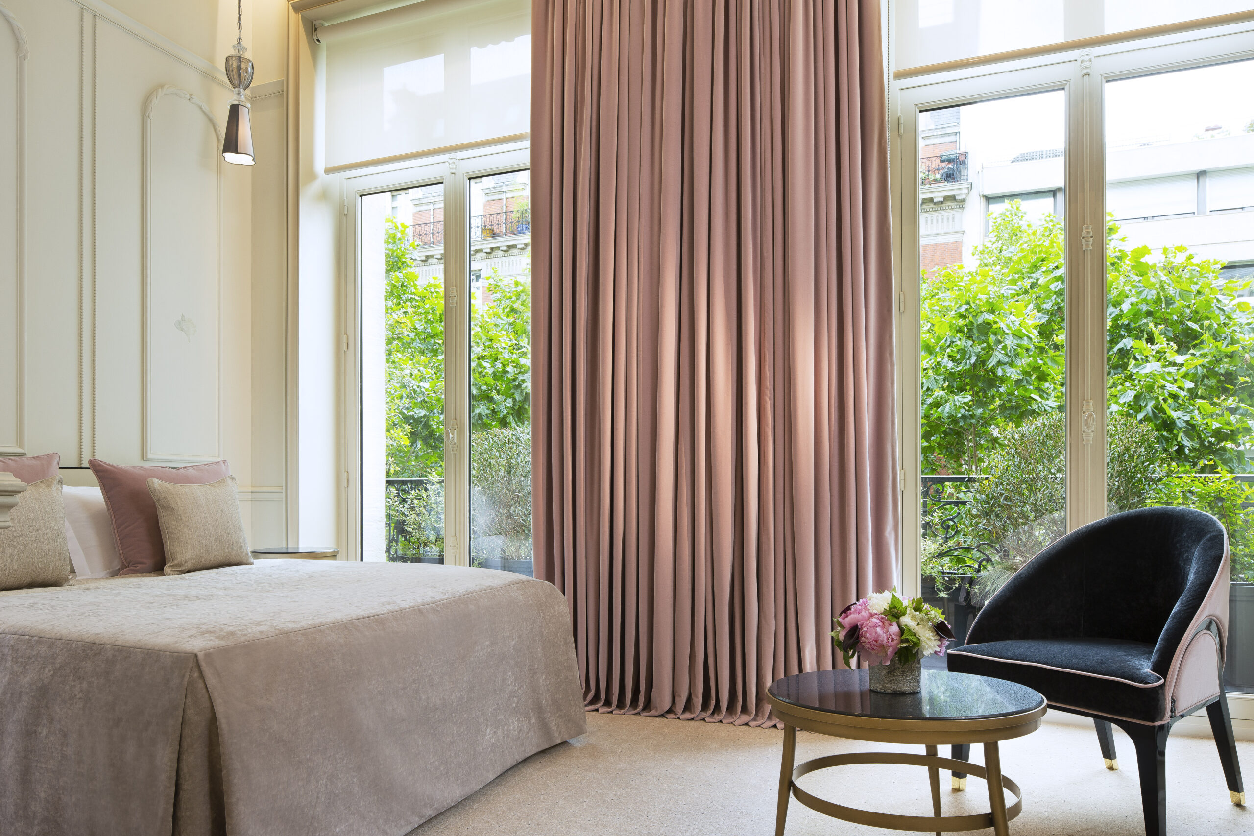 Superior guest room at Le Narcisse Blanc with rose pink curtains surrounding french doors overlooking greenery
