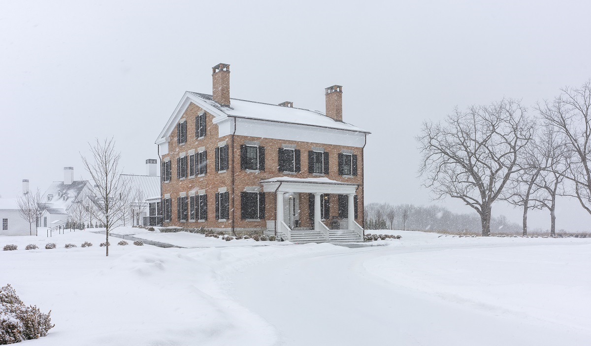 exterior view of historic farmhouse at Inns of Aurora in the snow