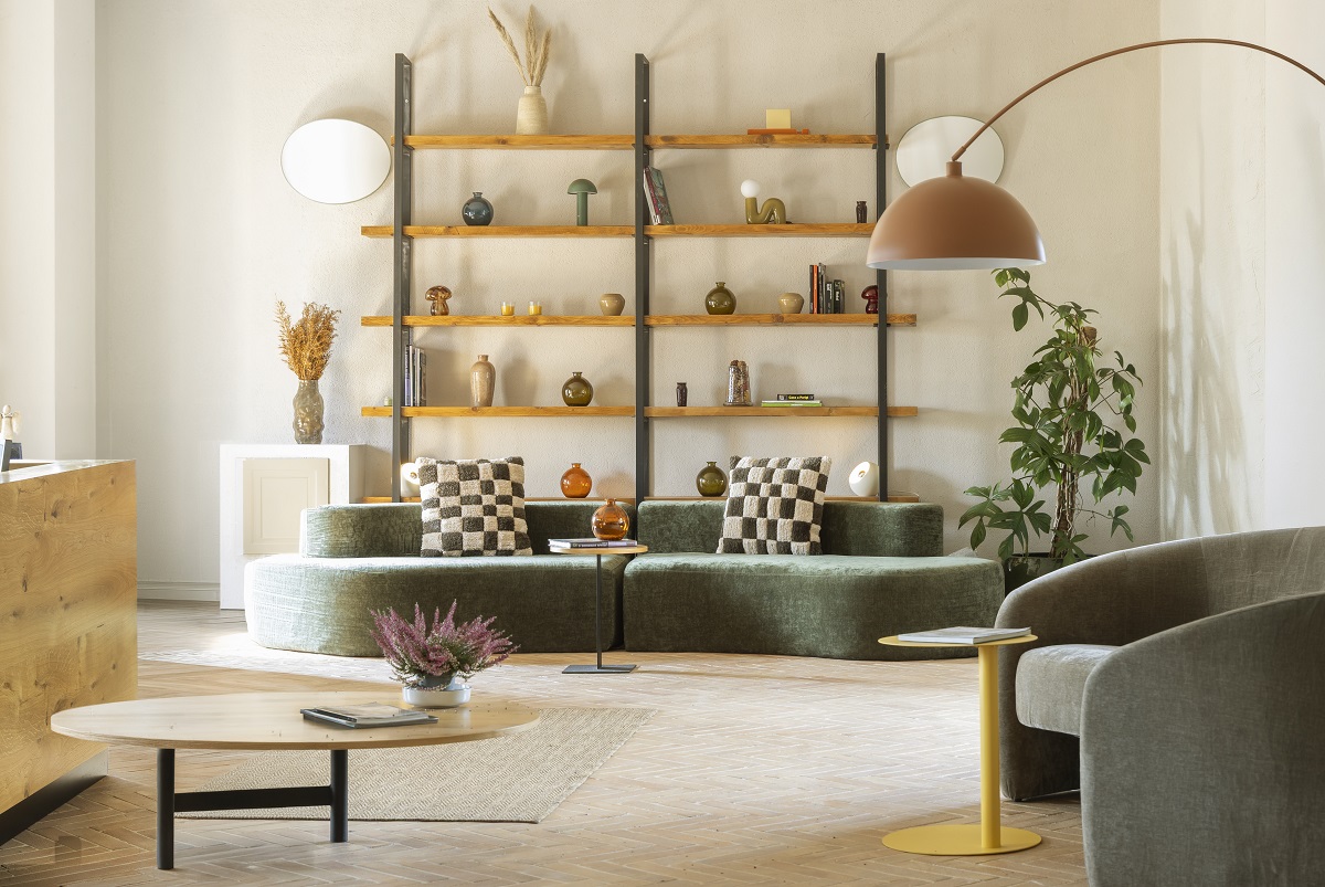 green curved couch in front of minimalist shelving with ceramics on display