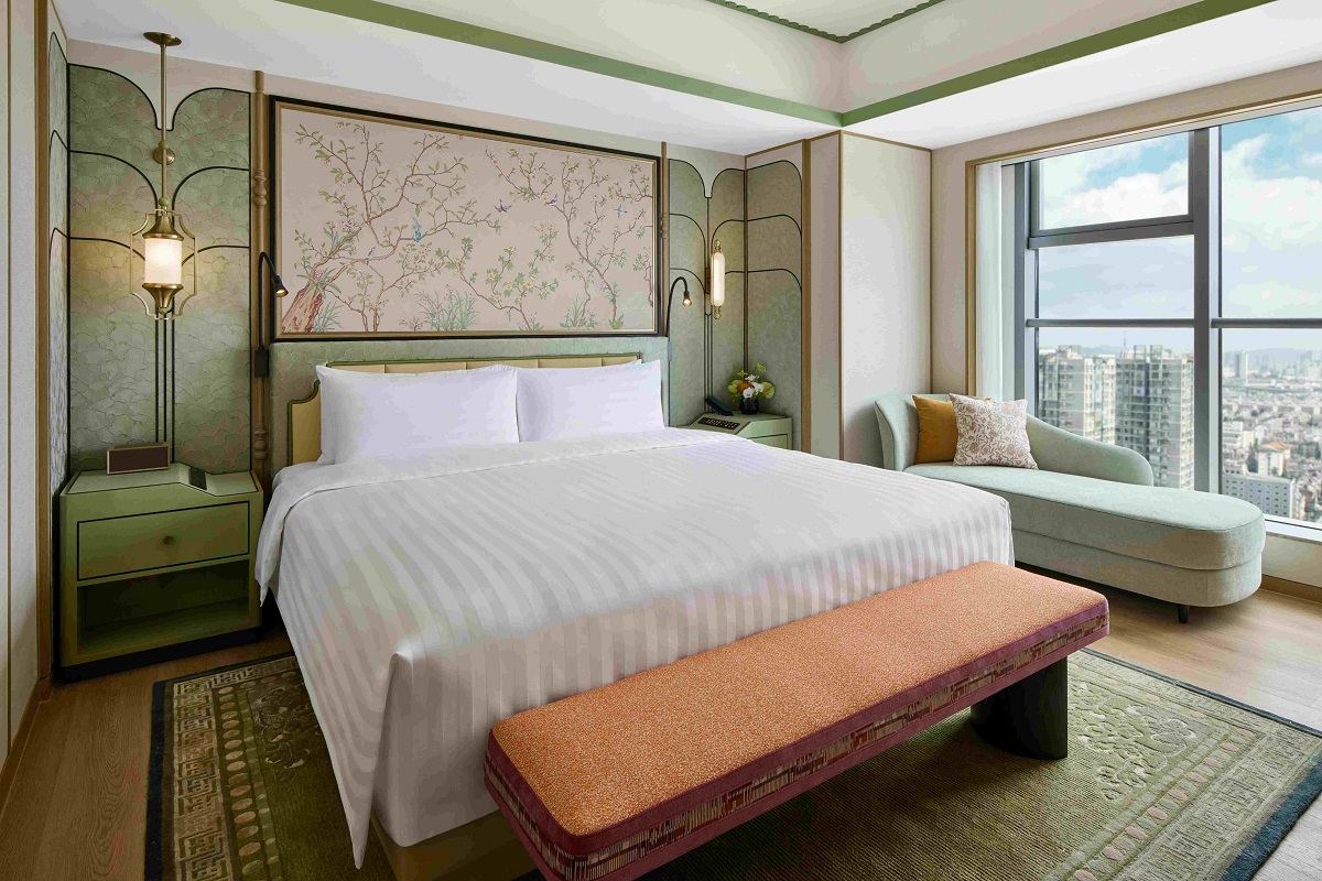 double bed in premier suite shangri-la kunming with cherry blossom wallpaper behind the bed and city views from window