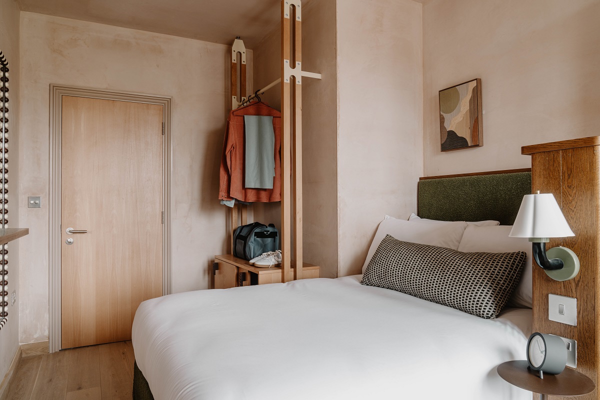 Belsize Park Studio bed with white linen , open wardrobe and wooden surfaces