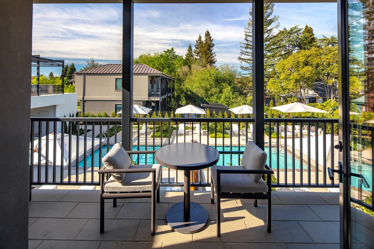 table and chair on guestroom terrace overlooking pool and garden