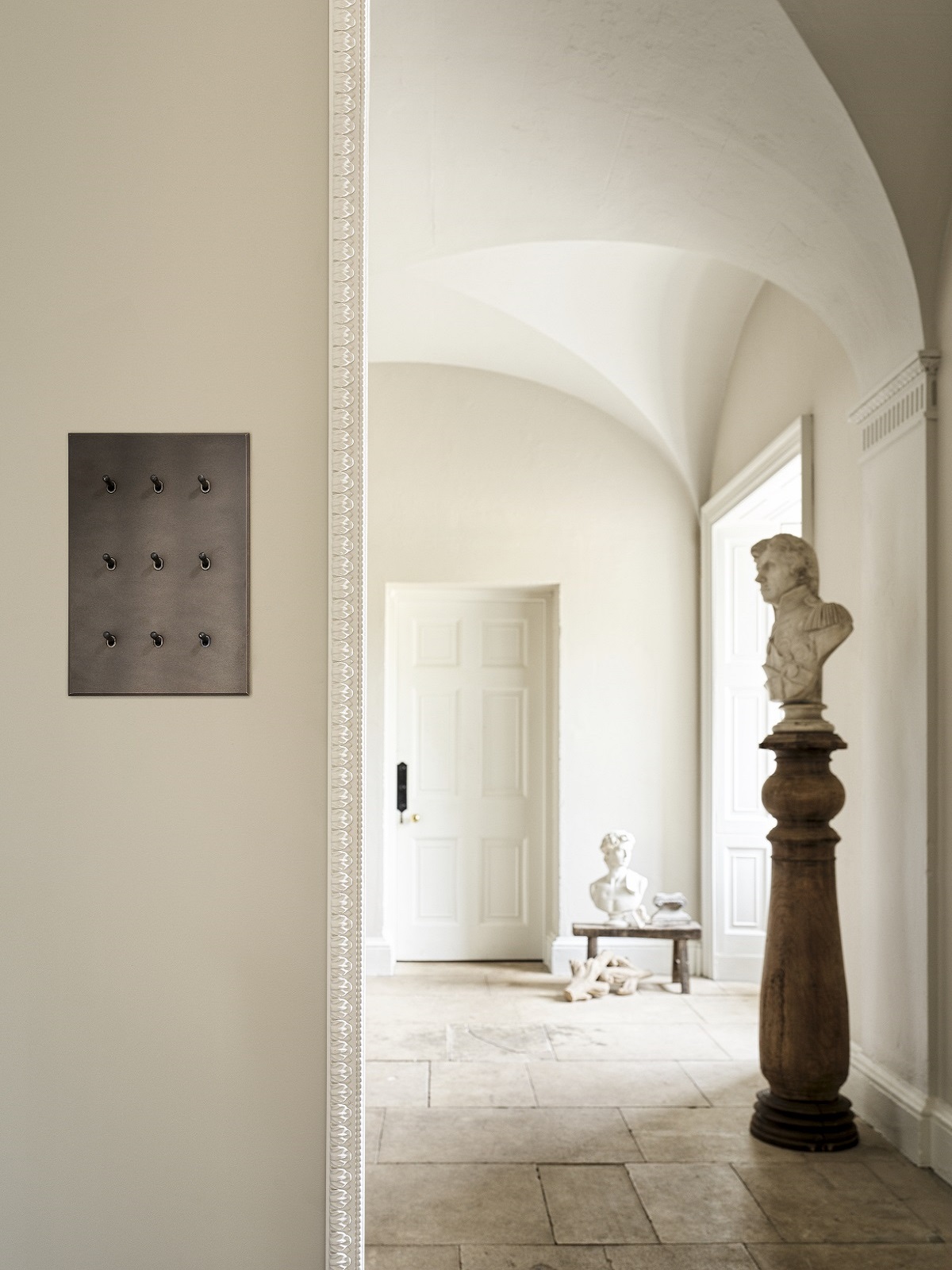 bronze light switch in hall with marble bust