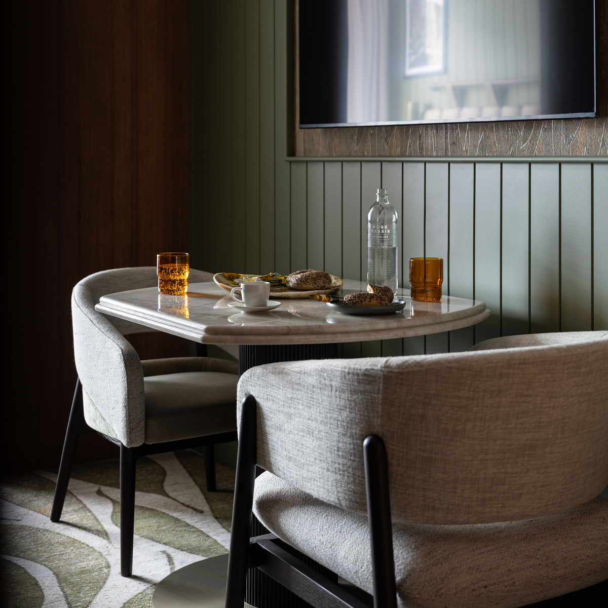 2 chairs at a table against olive green wood panelled wall