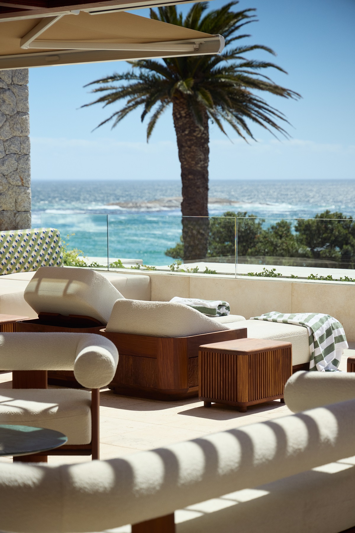pool deck at Morea House in cream and wood with view of palm tree and beach