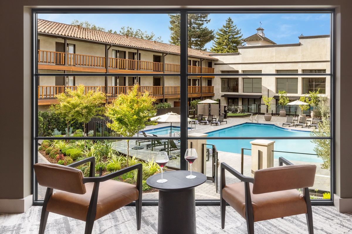 two chairs and table with wine glasses overlooking swimming pool