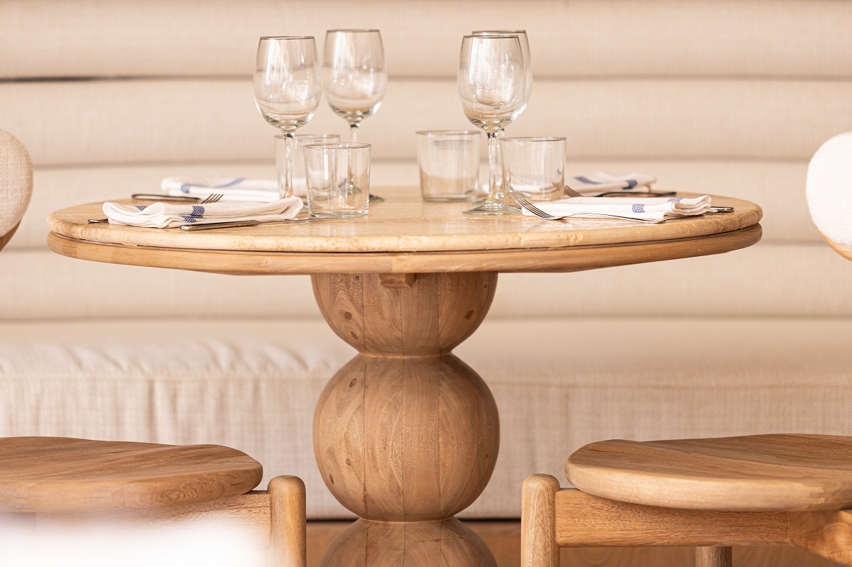 round wooden table , cream banquette and table setting in Evelina