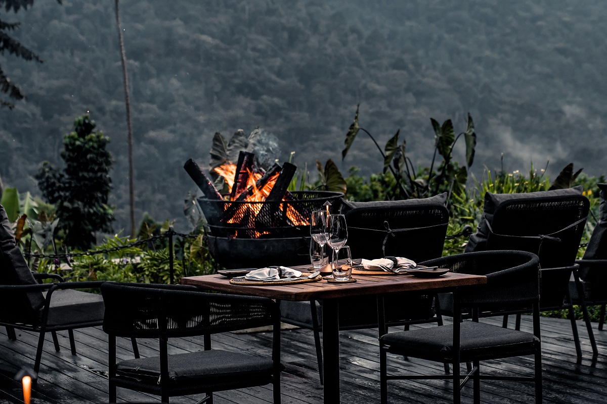 black wooden deck with firepit and black furniture overlooking mountains