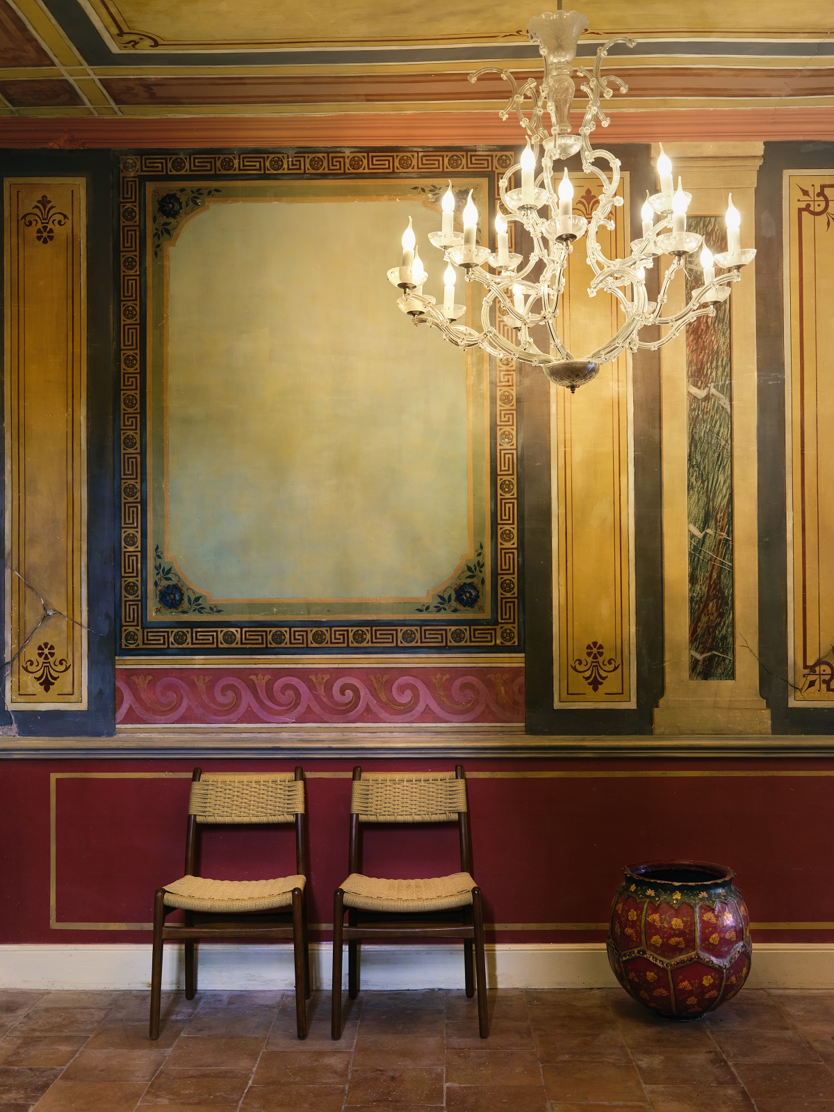 2 chairs below fresco and chandelier in Villa Augusta