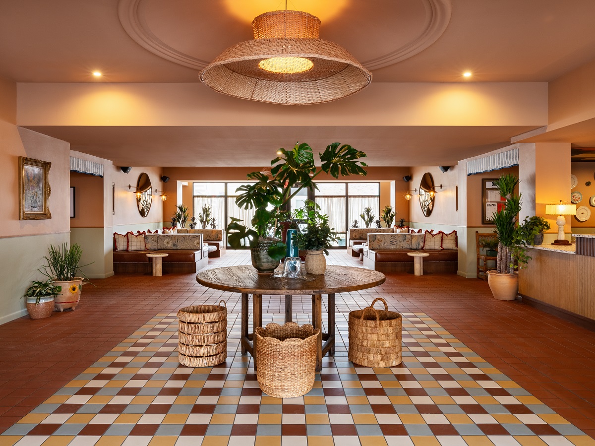 hotel lobby with tiled floor, wooden table, plants and baskets