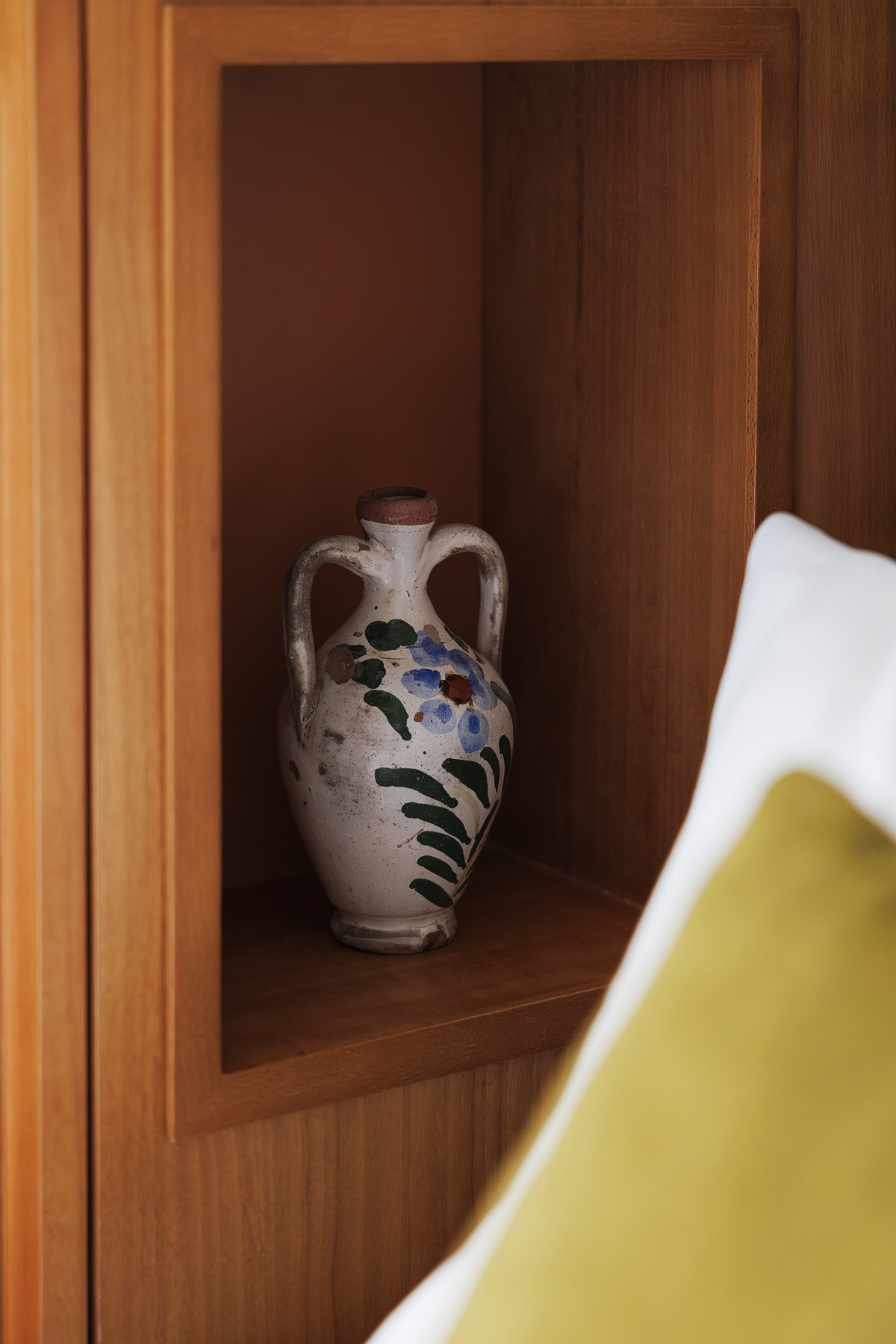 vintage vase in wooden niche next to bed