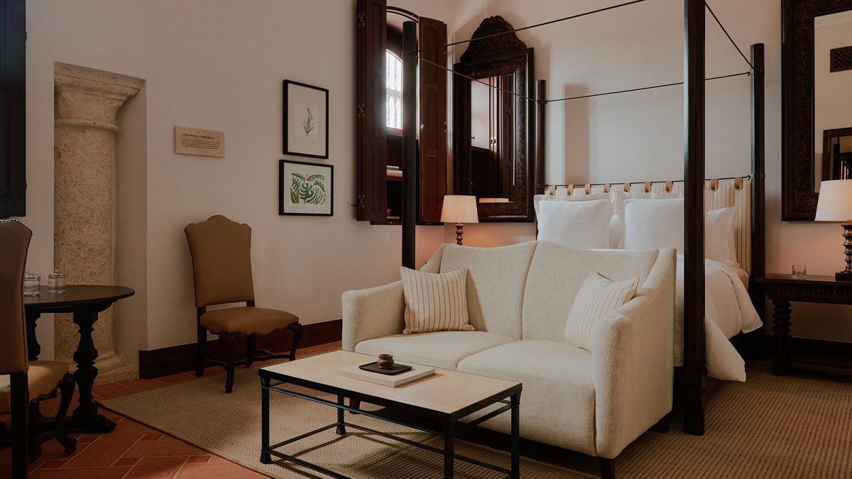 white couch in front of wooden four poster bed in four Seasons Cartagena